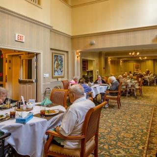 A cozy dining room with elderly people enjoying their meals.