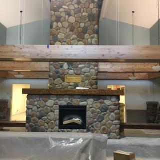 A beautifully designed interior space featuring a stone fireplace and wooden beams, showcasing a blend of natural materials and modern design.