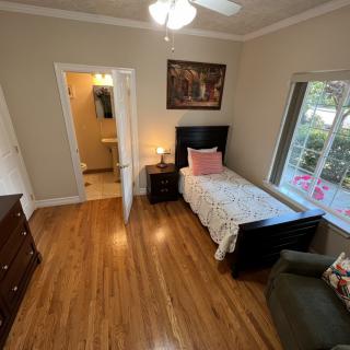 A cozy bedroom featuring a single bed, wooden floors, and a window view.