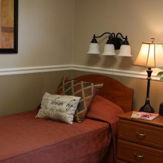 A cozy single bedroom featuring warm tones and simple decor.