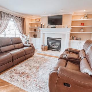 A cozy living room with leather sofas, a fireplace, and built-in shelves.