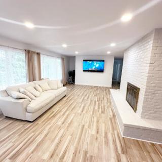 A bright and modern living room featuring a cozy sofa, a mounted television, and an elegant fireplace.