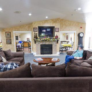 A cozy living room with a large sofa set, fireplace, and television, featuring a person seated comfortably.