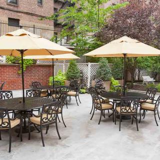 An inviting outdoor patio area with tables, chairs, and umbrellas surrounded by greenery.