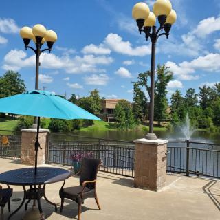 A scenic outdoor patio overlooking a lake with fountains and surrounded by greenery.