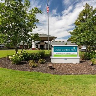 A hotel entrance with a prominent sign and well-maintained landscaping.