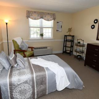 A cozy bedroom with a neatly made bed, stylish decor, and ample natural light.