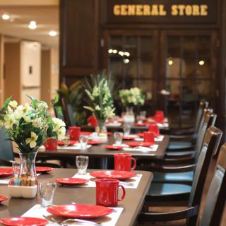 A beautifully set dining table with red crockery and flowers in a restaurant setting.