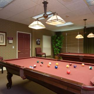 A game room featuring a pool table with balls arranged, under warm lighting.