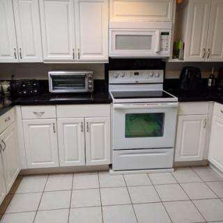 A modern kitchen featuring white cabinetry and black countertops, equipped with essential appliances.