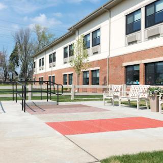 A view of a school playground area featuring accessible surfaces and benches, surrounded by green grass.