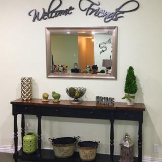 A warmly decorated entryway with a console table, mirror, and 'Welcome Friends' sign.