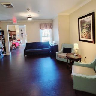 A cozy living room with sofas, chairs, a small table with a lamp, and a painting on the wall.