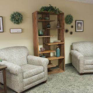 A cozy living room setup featuring two comfortable chairs and a wooden bookshelf decorated with plants and decorative items.