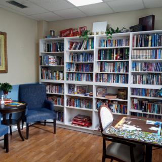 A cozy reading area with bookshelves filled with a variety of books, accompanied by comfortable chairs and a table.