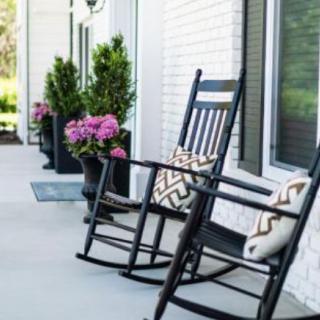 A cozy porch with black rocking chairs and potted plants.