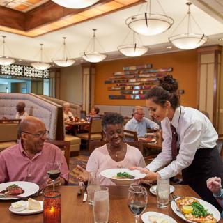 A waitress serves food to a group of people dining at a restaurant.