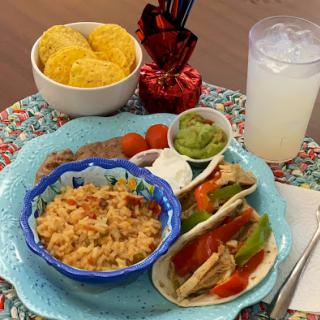 A vibrant Mexican meal featuring tacos, rice, guacamole, and a refreshing drink.