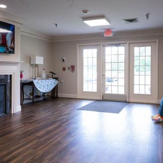 A cozy living room with a fireplace, television, and large windows.