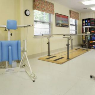 A well-equipped physical therapy room with parallel bars and exercise equipment.