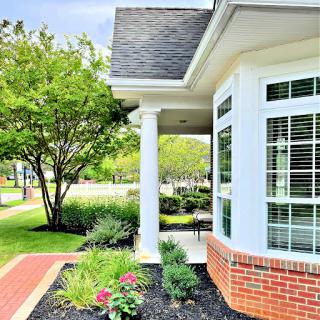 A picturesque view of a house featuring elegant columns and a vibrant garden.