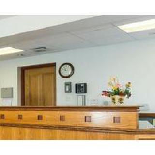 A reception desk with a clock on the wall and a vase of flowers.