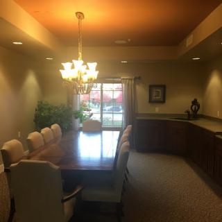 A spacious dining room featuring a large wooden table surrounded by elegant chairs, illuminated by a chandelier.