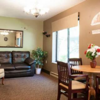 A cozy living room with a sofa, dining table, mirror, and large window.