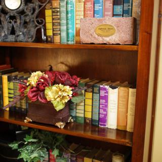 A cozy bookshelf filled with colorful books and adorned with a decorative floral arrangement.