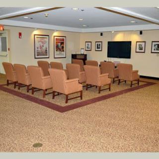 A conference room with arranged seating facing a television screen and framed pictures on the walls.