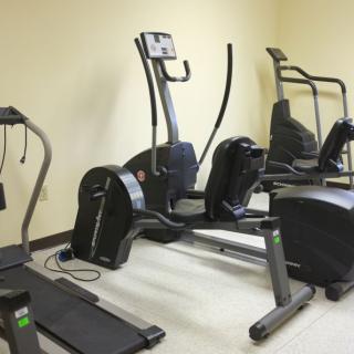 A small fitness center with various exercise machines, including a treadmill and elliptical trainers.