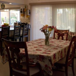A cozy dining room with a floral tablecloth and a vase of flowers on the table.