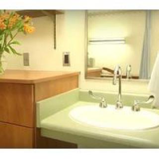 A clean and modern bathroom sink area with a mirror and flowers on the countertop.