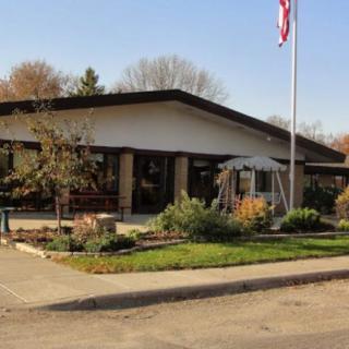 A building with a garden and flagpole in front, surrounded by trees.