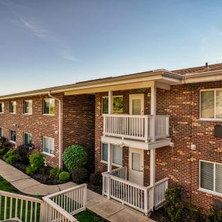 A brick apartment building with balconies and well-maintained landscaping.