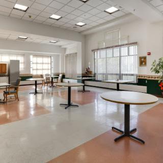 A spacious and well-lit room featuring multiple tables and chairs, designed for gatherings or activities.