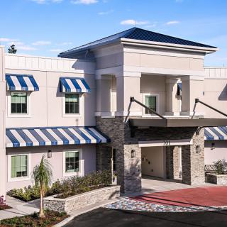A modern building with striped awnings and a prominent entrance under a clear sky.