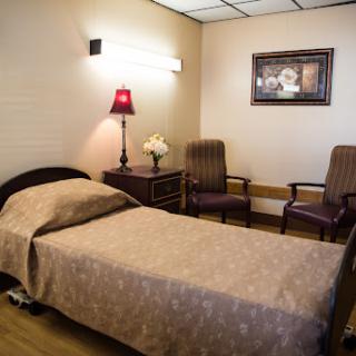 A cozy hospital room featuring a bed, chairs, and decorative elements.