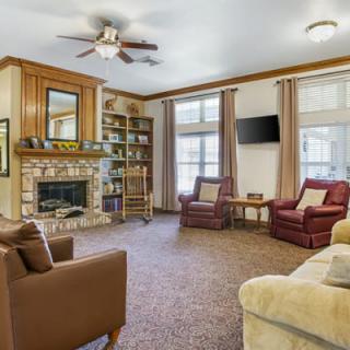 A cozy living room with a fireplace, comfortable seating, and a bookshelf.