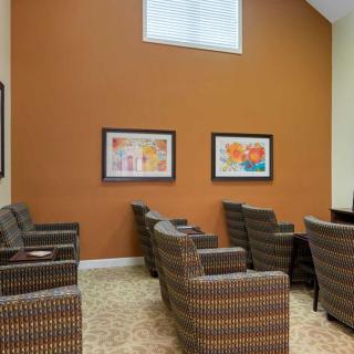 A modern waiting room with patterned chairs and colorful artwork on an orange accent wall.
