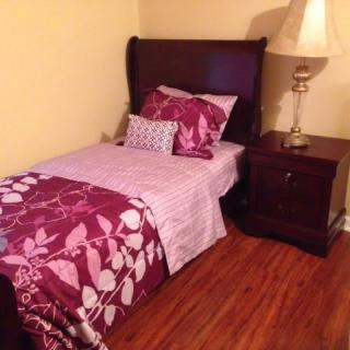 A cozy bedroom with a single bed featuring floral bedding, a nightstand, and a lamp.