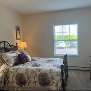A cozy bedroom with a bed, lamp, and window view.
