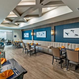 A modern restaurant interior featuring stylish tables and chairs, artwork on the walls, and elegant lighting.