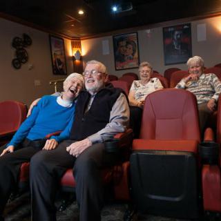 Elderly couples enjoying a movie in a cozy theater setting.