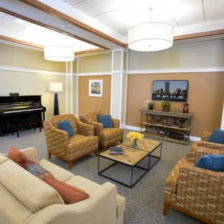 A cozy living room featuring comfortable seating, a piano, and modern decor.