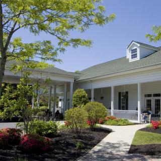 A picturesque view of a well-maintained building with a garden and pathway on a sunny day.