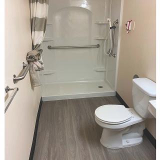 An accessible bathroom featuring a shower with grab bars and a toilet.