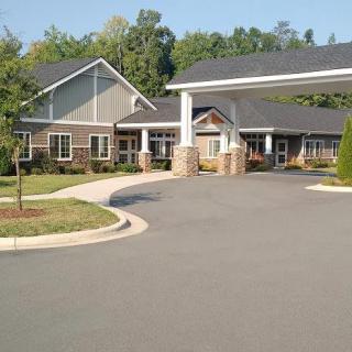 A view of a building with a driveway and landscaped surroundings.