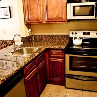 A modern kitchen with granite countertops, stainless steel appliances, and wooden cabinets.