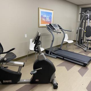 A small gym room with exercise equipment, including a treadmill and a stationary bike.